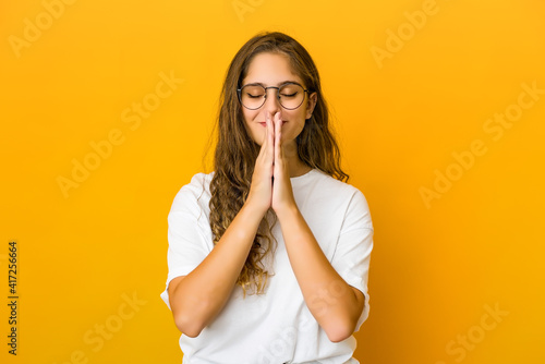 Young caucasian woman holding hands in pray near mouth, feels confident. photo
