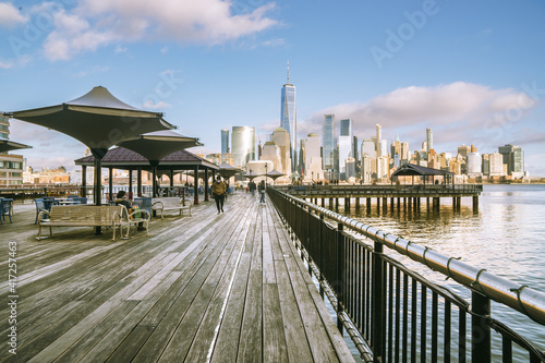 Jersey City, NJ - USA - Feb. 27, 2021: Landscape sunset view of people enjoying the riverfront at J Owen Grundy Park  with the lower Manhattan skyline in the distance, © Brian