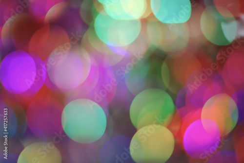 Bokeh lights background of brightly colored blurry garlands at night, disco party design