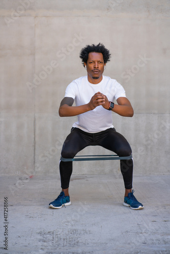 Afro athletic man doing exercise outdoors.