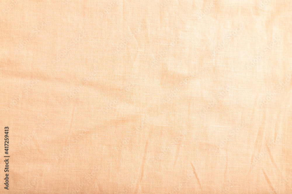 Fragment of smooth orange linen tissue. Top view, natural textile background.