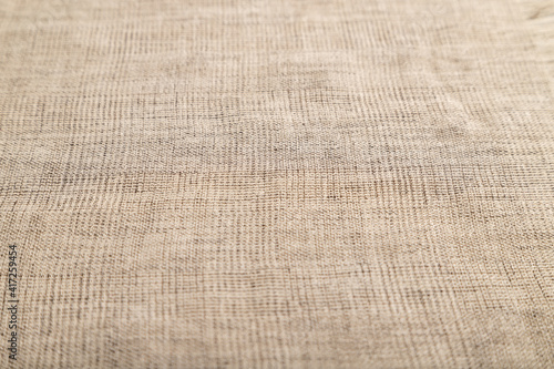 Fragment of smooth brown linen tissue. Side view, natural textile background.