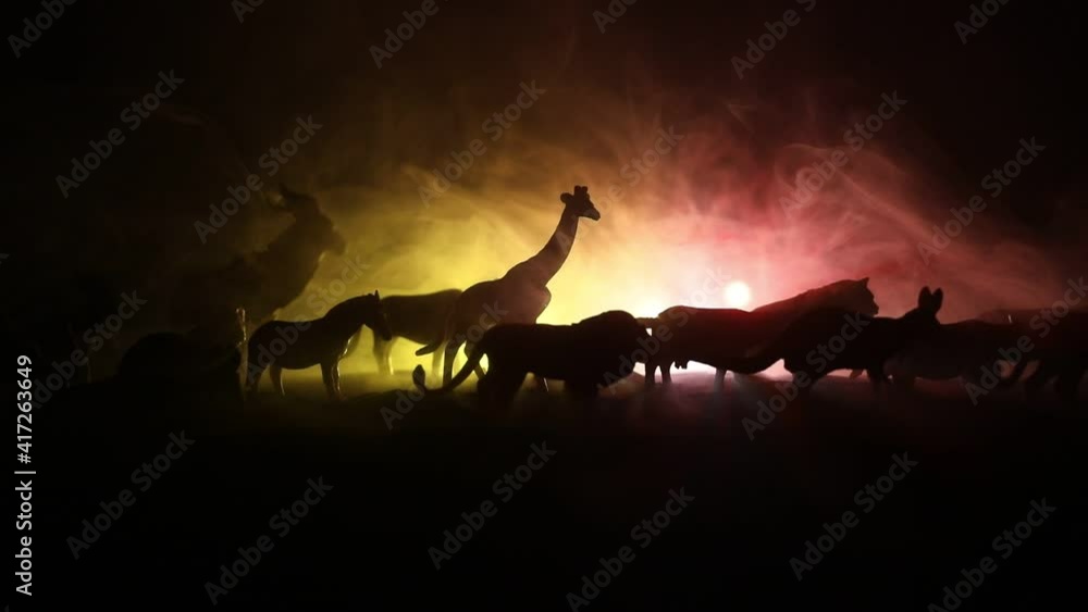 A group of animals are grouped together at foggy night with burning colorful background. Animals Running Escaping to Save Their Lives from fire. Selective focus.