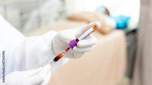 Hand of nurse, doctor or medical technologist in white gloves with  syringe taking blood sample from a patient in the hospital, Doctor drawing blood sample from arm for blood test.