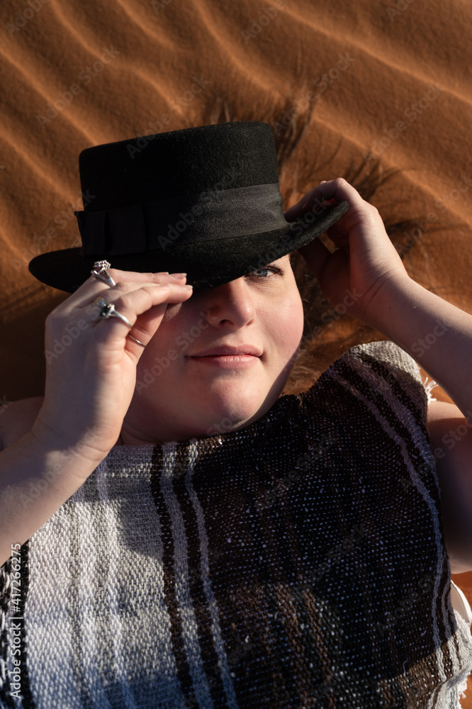 woman lying naked in the desert sand dunes with a native blanket and black hat woman lying naked in the desert sand dunes with a native blanket and black hat