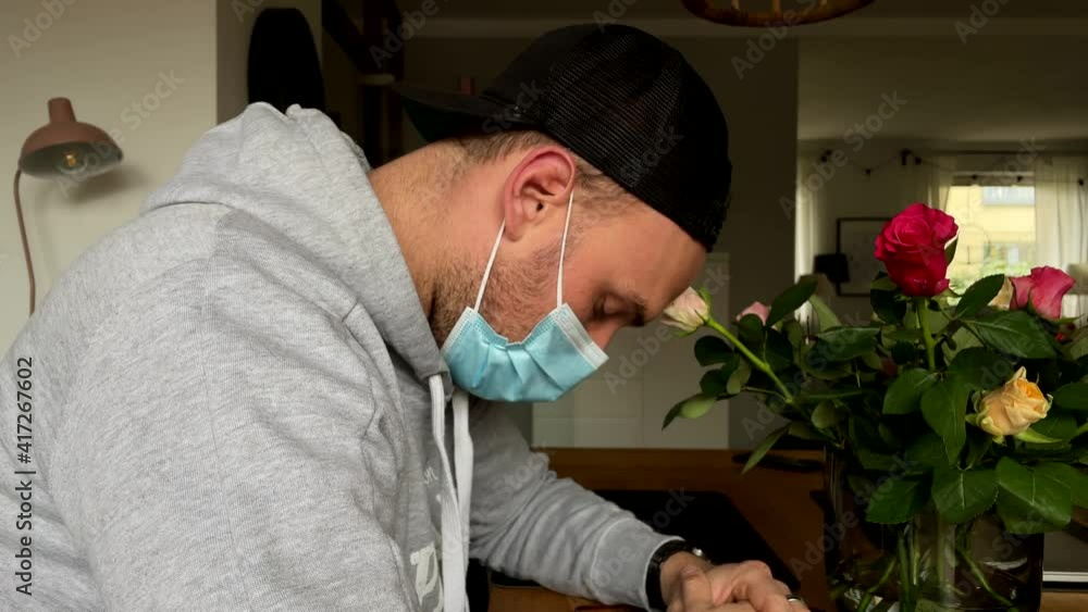 Sad caucasian man with protection mask mourning and grieving in front of roses after death of grandmother. Corona Virus Covid-19 Pandemic. Sad caucasian man with protection mask mourning and grieving in front of roses after death of grandmother. Corona Virus Covid-19 Pandemic.