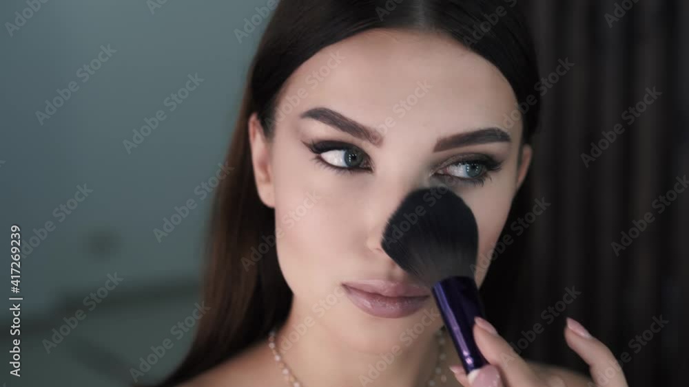 Close-up of pretty young brunette girl applying makeup using brush Close-up of pretty young brunette girl applying makeup using brush