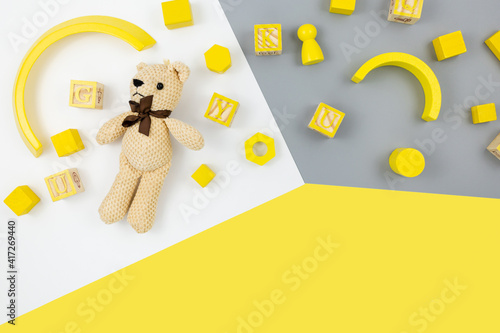 Wooden toys, blocks, bear on yellow gray background. Trendy cute baby first toys. Eco-friendly, plastic-free set of accessories for kids. Toys for kindergarten, preschool or daycare. Close up 