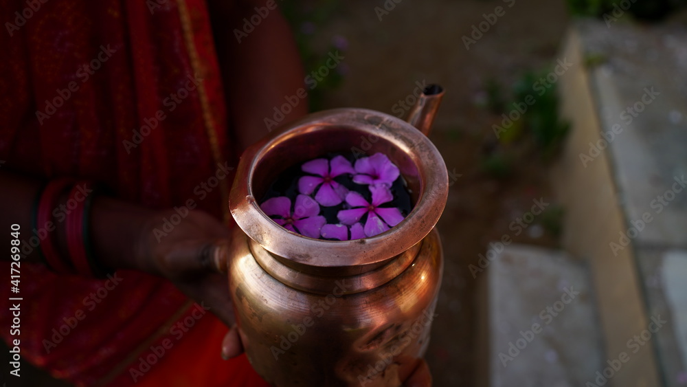 Copper Kalsh full of sacred water and aroma flowers. Sacred Kalash or Mug to worship God. Hindu religion concept.