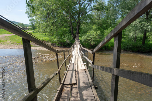 Suspended wooden bridge over a small river. Summer landscape. photo