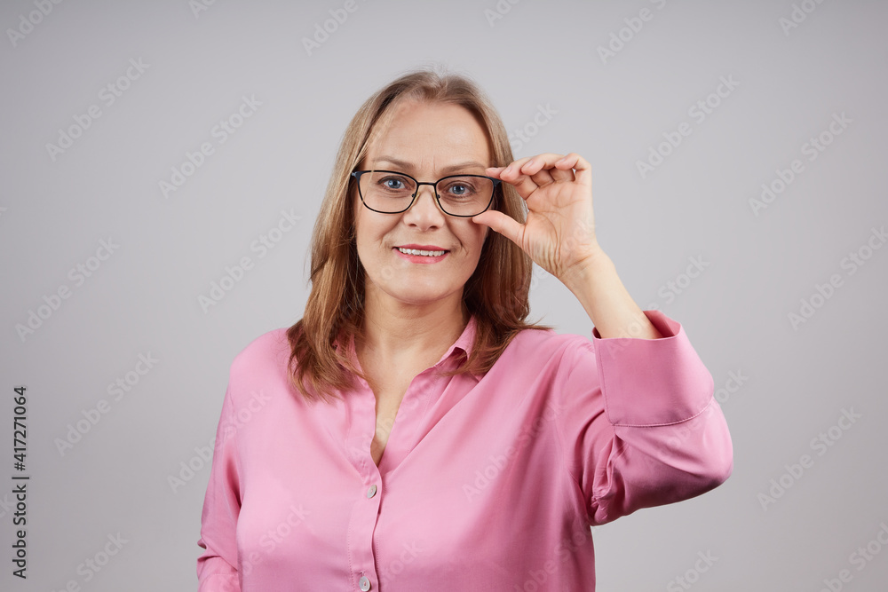 Portrait of senior businesswoman in pink blouse wearing glasses. Isolated photo on gray background, with copy space. Portrait of senior businesswoman in pink blouse wearing glasses. Isolated photo on gray background, with copy space.
