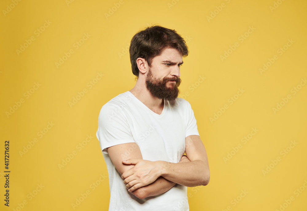 Emotional guy gesturing with his hands on a yellow background model side view Emotional guy gesturing with his hands on a yellow background model side view