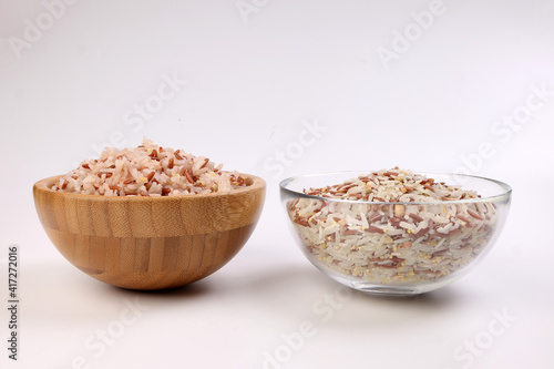 Cooked and raw mixed low glycaemic index healthy rice grain basmati millet buckwheat red rice in wooden and glass bowl on white background photo