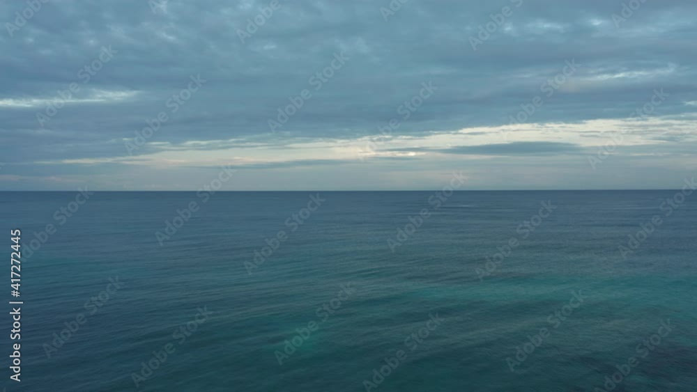 The Caribbean Ocean vanishes into the horizon with cloudy skies towards sunset. The Caribbean Ocean vanishes into the horizon with cloudy skies towards sunset.