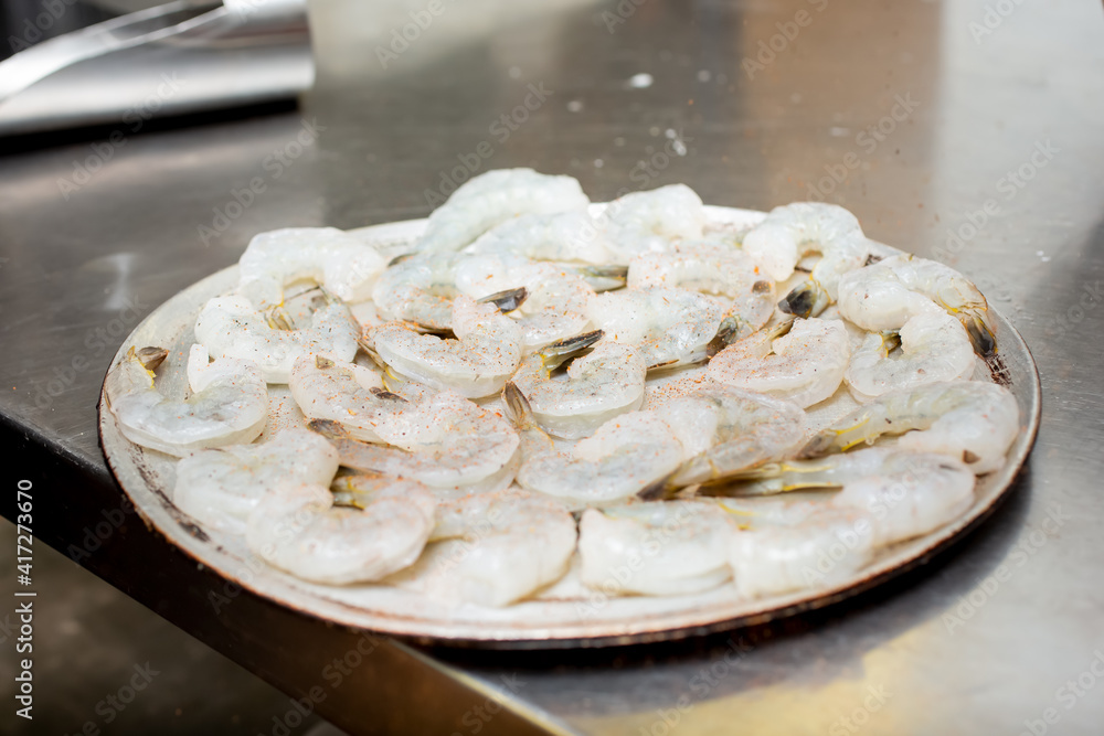 A view of a tray of raw shrimp on a metal counter. A view of a tray of raw shrimp on a metal counter.