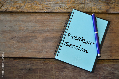 Notebook written with text BREAKOUT SESSION over wooden background.