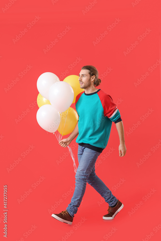 Handsome young man with balloons on color background Handsome young man with balloons on color background