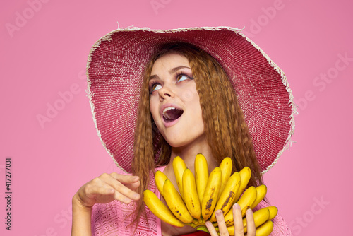 Woman with bananas in hands in hat exotic fruits lifestyle pink background