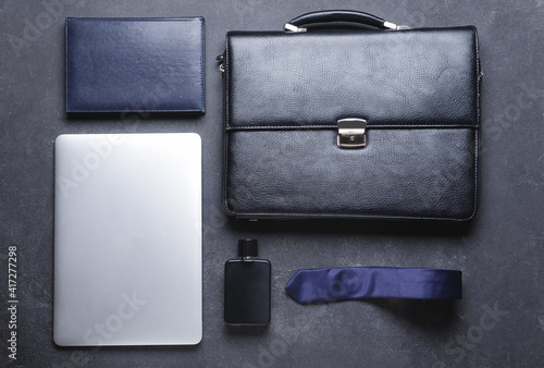 Stylish male accessories and laptop on dark background
