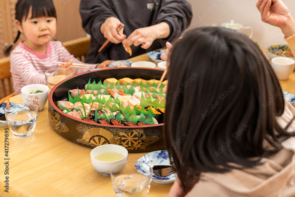 自宅で出前寿司を食べる家族