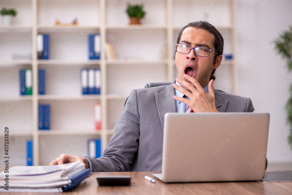 Young male employee sitting at workplace Young male employee sitting at workplace