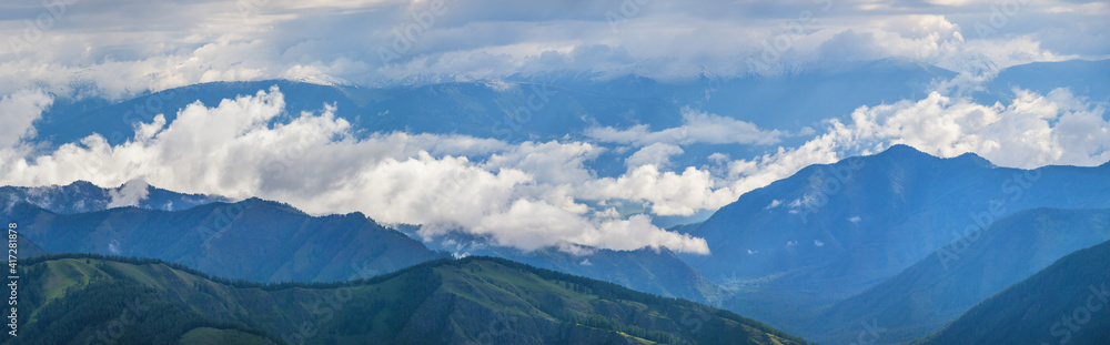Mountains in clouds and fog on a summer morning, panoramic view