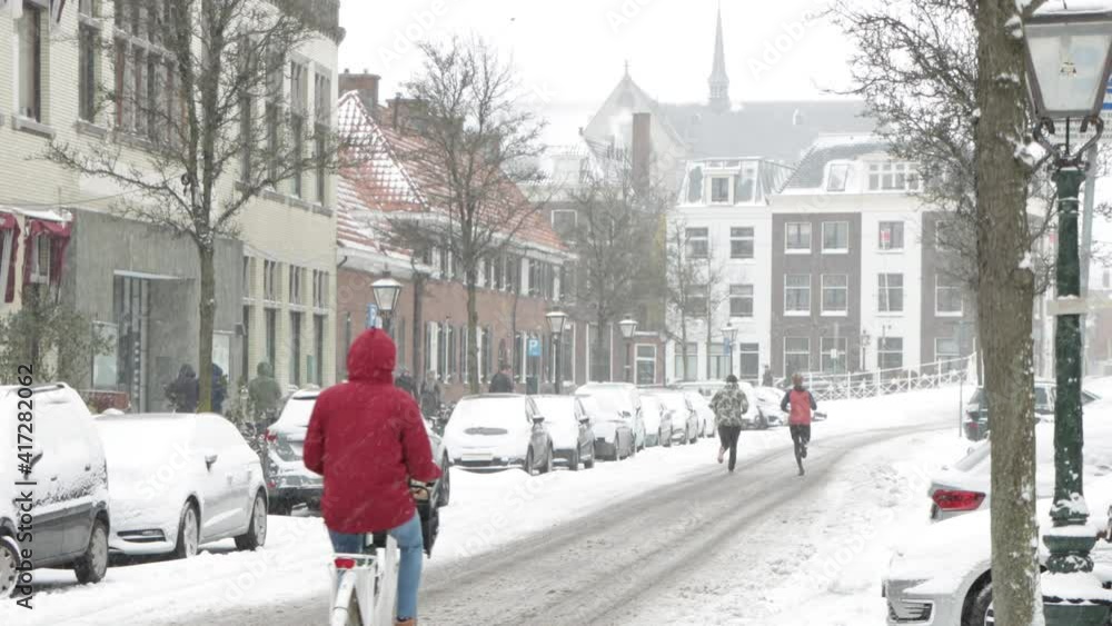 People running and cycling on a snowy street in Leiden, the Netherlands during the pandemic People running and cycling on a snowy street in Leiden, the Netherlands during the pandemic