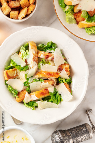 Caesar salad, shot from above on a white marble background