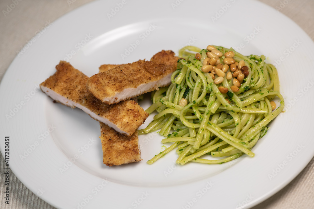 Turkey cutlet and Green spinach spaghetti with cheese and tomato on table