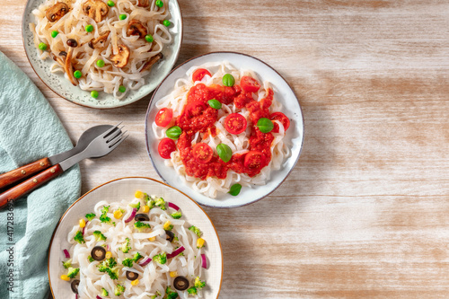 Konjac pasta with various vegetables, shot ftom the top with a place for text on a wooden background photo