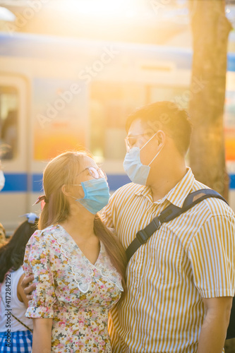 Young millennials couple wearing protective face masks and showing their love outdoor in Ho Chi Minh City during Covid-19