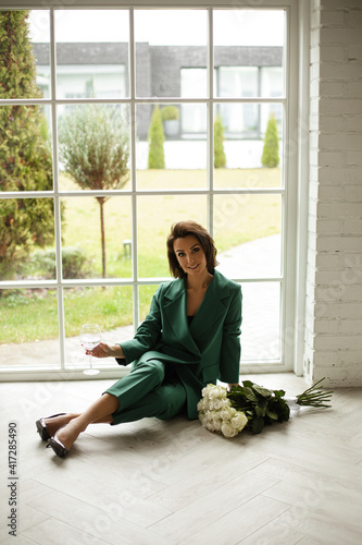 Принти на полотні elegant caucasian woman with dark hair in green suit poses for the camera near t