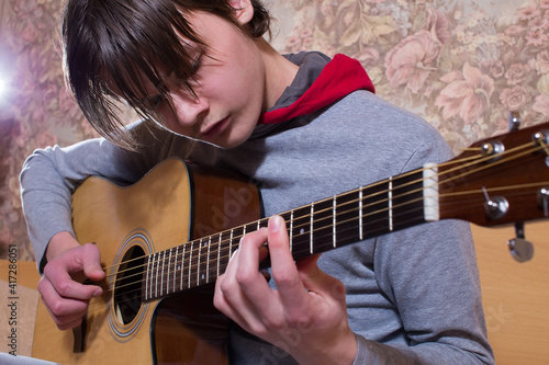 A young man is learning to play the guitar.