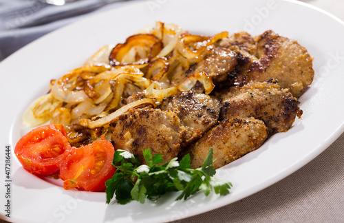 Tasty rabbit liver fried with onion garnished with fresh parsley and blanched cherry tomatoes