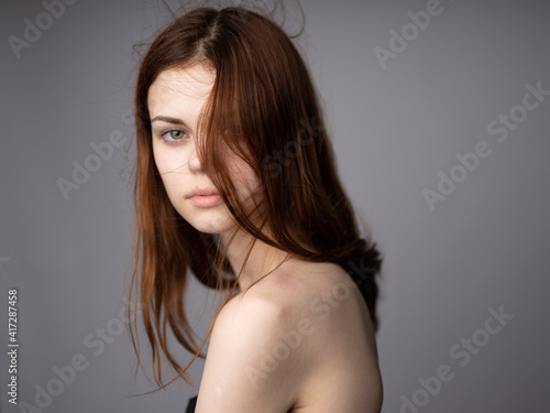 Side view portrait of woman with bared shoulders for gray background