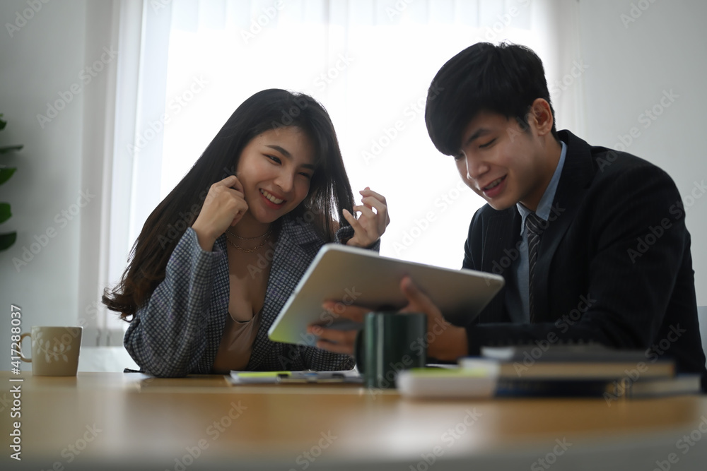 Smart businessman showing business data on digital tablet to his colleague and discussing company financial strategy in meeting room.