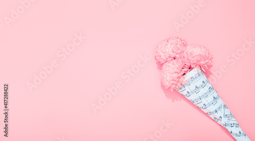 Chrysanthemums bouquet wrapped in a sheet with musical notes on pink background with copy space. Holiday theme of music lovers. Happy Valentine Day February 14. Woman Day March 8. Mother Day May 8
