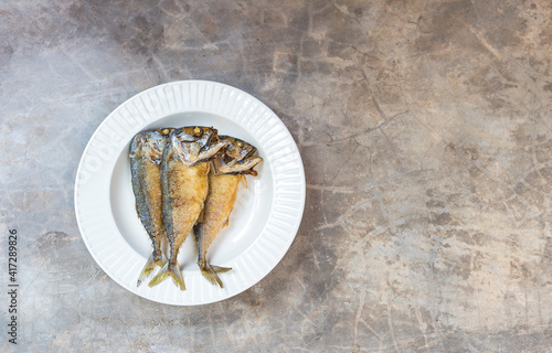 Crispy deep fried mackerel fish on round ceramic plate with space on grey cement floor texture background  healthy food  easy cooking fish dish