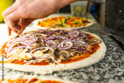 Pizaiolo Preparing Pizza in Restaurant with Fresh Ingredients. Chef at Work photo