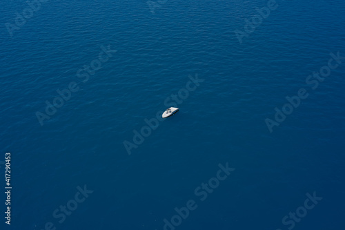 Lonely boat mooring on the water. Drone view of a boat. Aerial view of a yacht on blue water. Top view of a white boat in the blue sea. luxury motor boat.