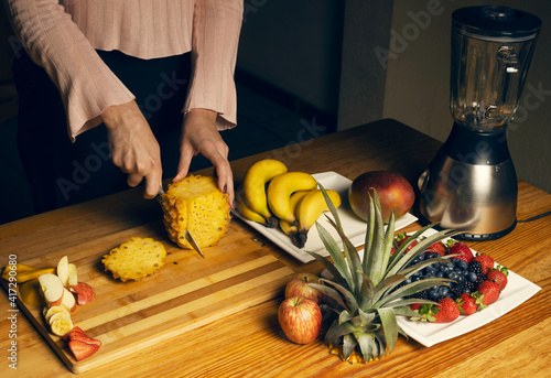 Girl cutting a pineapple for a smoothie