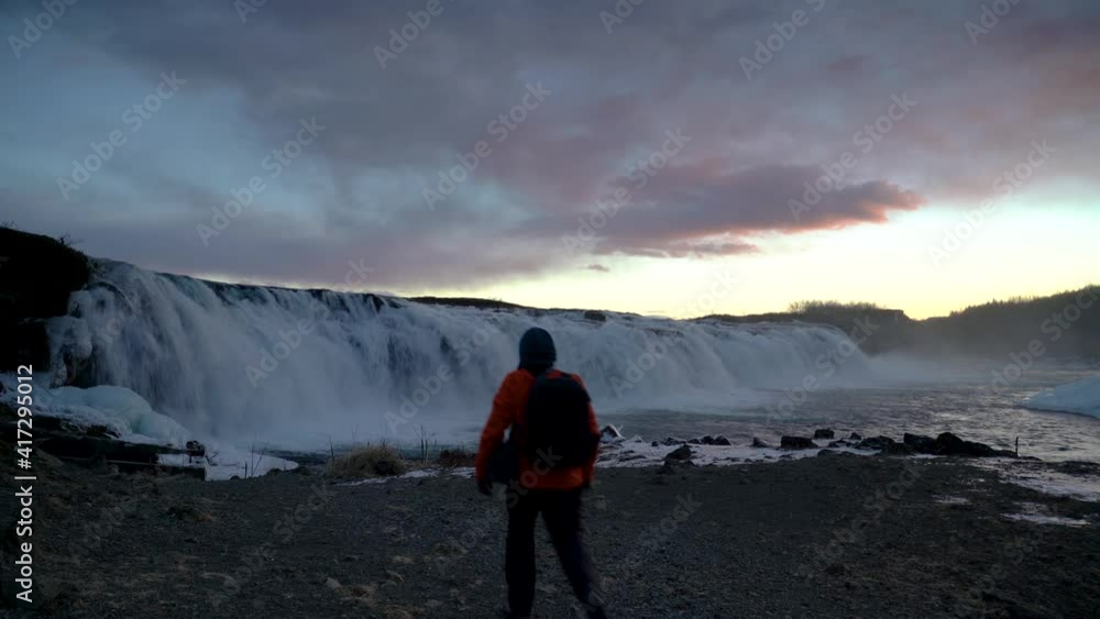 Man With Backpack Walk Towards Faxi Waterfall in Iceland. - wide shot Man With Backpack Walk Towards Faxi Waterfall in Iceland. - wide shot