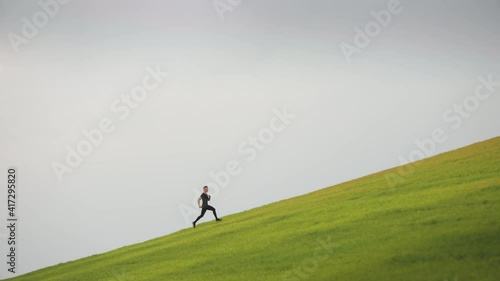 Wallpaper Mural The man is running up. He is running out onto the green slope. Running training. 4K. Torontodigital.ca