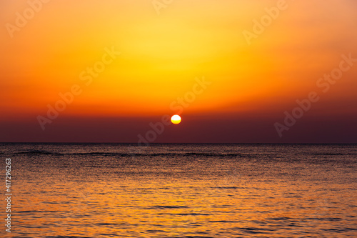 Bright sunset with a big yellow sun under the sea surface.