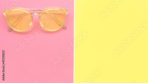 Modern fashionable sunglasses on pink and yellow background