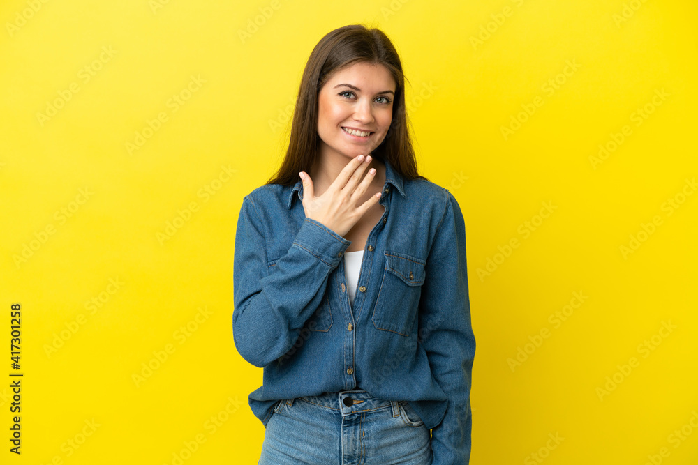 Young caucasian woman isolated on yellow background looking up while smiling Young caucasian woman isolated on yellow background looking up while smiling