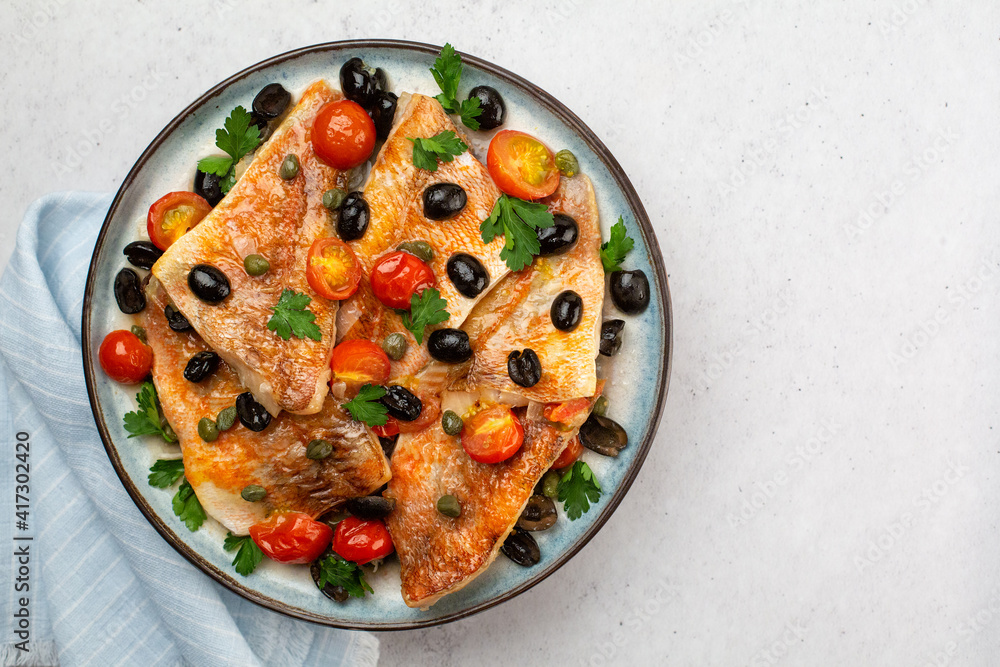 Perch fish fillets stew, italian style, with black olives, tomatoes and