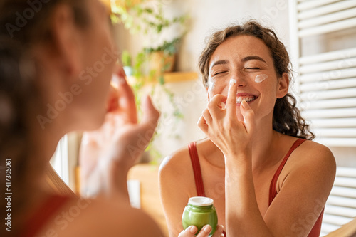 фотографія Joyful beauty woman applying cream on face