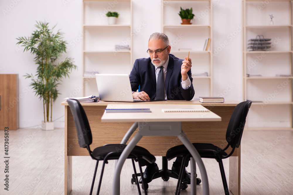 Old male employer sitting in the office Old male employer sitting in the office