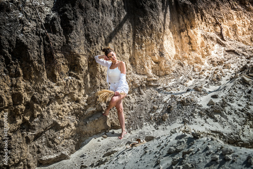 slim sporty girl in a casual clothes posing against the rocks of sand in quarry © RomanR